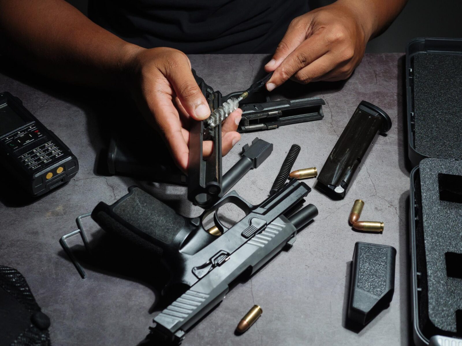 Gunsmith cleaning a stripped pistol slide at the bench